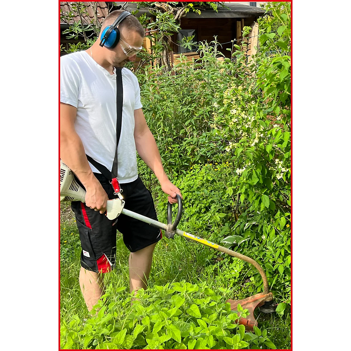 Ein Mann schneidet mit einem Freischneider Gras. Er trägt Gehörschutz und eine Schutzbrille.